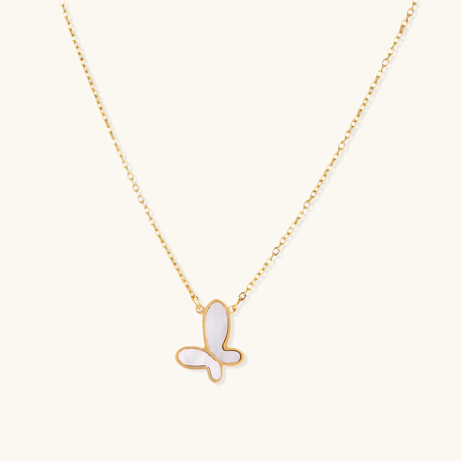 Delicate gold butterfly necklace with white mother of pearl wings on fine chain, displayed on neutral background.