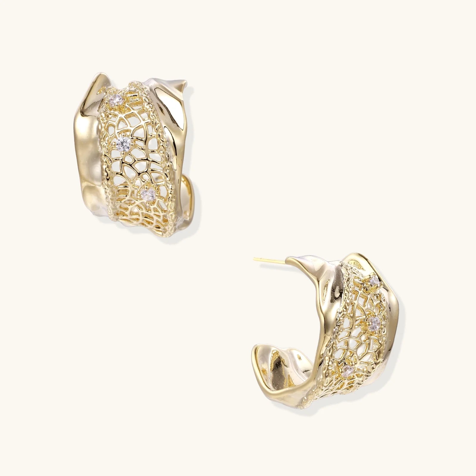 Gold-plated sculptural hoop earrings with geometric lattice centerband and sparkling zirconia on white background.