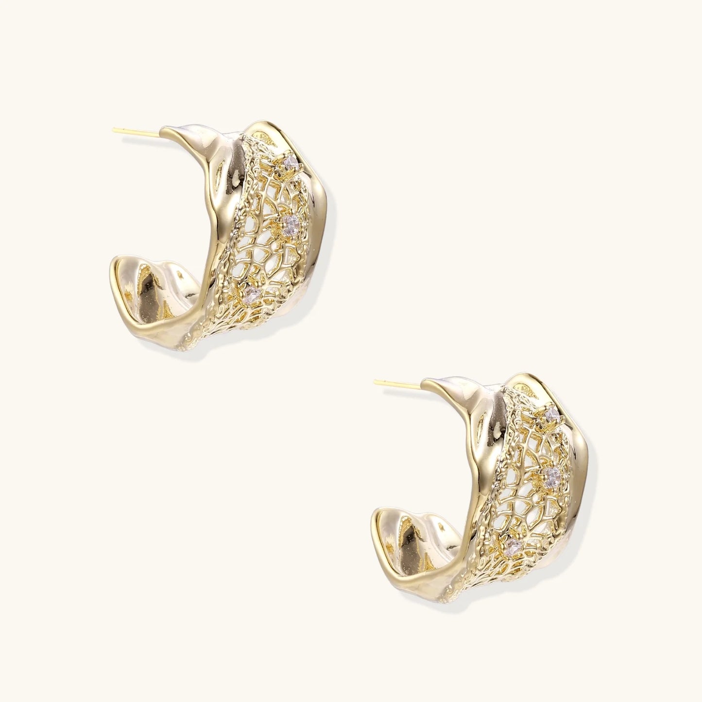 Gold-plated sculptural hoop earrings with geometric lattice centerband and sparkling zirconia on white background.