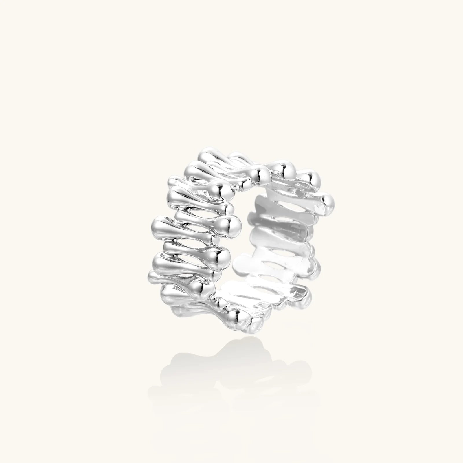 Wide band ring with sculptural wave ripples in polished white gold plated eco-brass on cream background