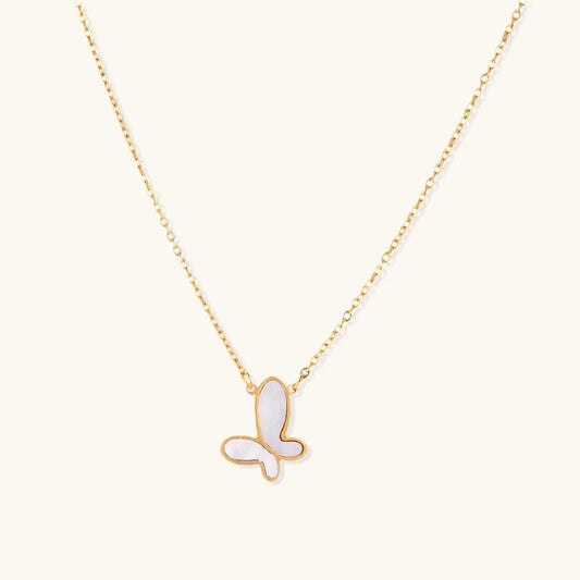 Gold-plated butterfly pendant with iridescent mother of pearl inlay on delicate chain against cream background.